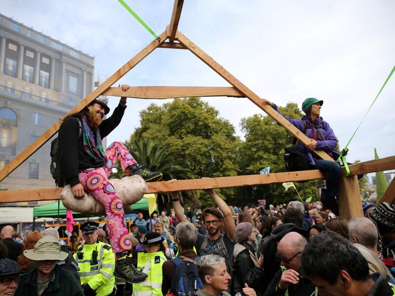 Climate change activists from the group Extinction Rebellion sit atop a temporary wooden structure as they demonstrate on Lambeth Bridge in central London, on October 7, 2019. Extinction Rebellion has scheduled non-violent protests chiefly in Europe, North America and Australia over the next fortnight. ISABEL INFANTES / AFP