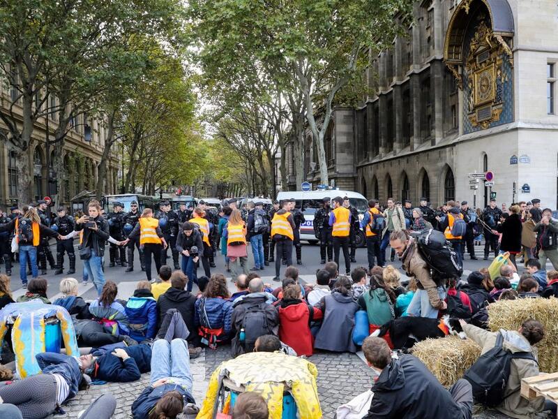 French Gendarmes stand ready as protesters sit on the ground to block the Pont au Change bridge during a demonstration called by climate change activist group Extinction Rebellion, on October 7, 2019 in front of the Conciergerie in Paris. AFP