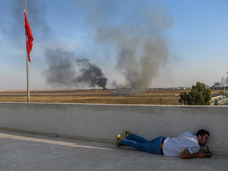 A journalist takes cover in Akcakale near the Turkish border with Syria on October 10, 2019 as a mortar landed nearby, on the second day of Turkey's military operation against Kurdish forces. (AFP)