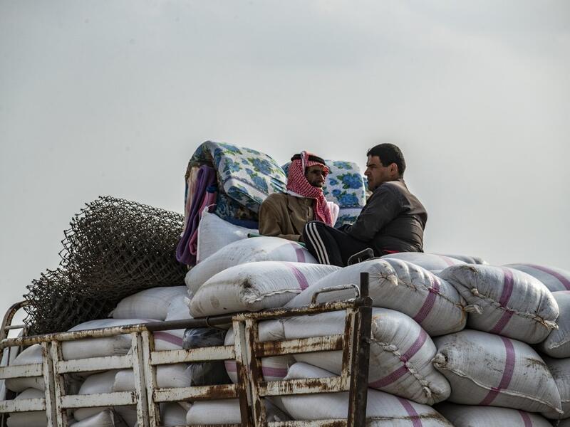 Syrian men flee with their belongings the countryside of the northeastern Syrian town of Ras al-Ain on the Turkish border, toward the west to the town of Tal Tamr on October 19, 2019. Turkey's President Recep Tayyip Erdogan fired off a fresh warning today to "crush" Kurdish forces as both sides traded accusations of violating a US-brokered truce deal in northeastern Syria. Delil SOULEIMAN / AFP