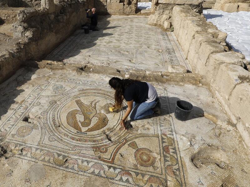 Timnah Goloubin (L), an archaeologist with the Israel Antiquities Authority, shows on October 23, 2019 a mosaic church floor of an Eagle symbol of the Byzantine Empire in the Israeli town of Beit Shemesh. A magnificent 1500-year-old church, decorated with spectacular mosaic floors and Greek inscriptions, was discovered during a three-year excavation near a residential area. MENAHEM KAHANA / afp