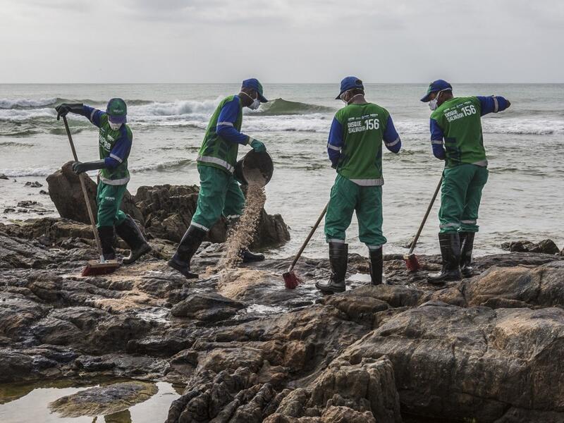 Municipal workers remove spilled crude oil at Pedra do Sal beach in Salvador, Bahia state, Brazil, on October 23, 2019. Large blobs of oil staining more than 130 beaches in northeastern Brazil began appearing in early September and have now turned up along a 2,000km stretch of the Atlantic coastline. The source of the patches remain a mystery despite President Jair Bolsonaro's assertions they came from outside the country and were possibly the work of criminals. ANTONELLO VENERI / AFP
