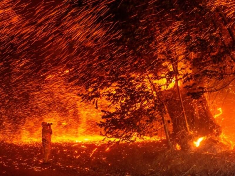 A photographer takes photos amid a shower of embers as wind and flames rip through the area during a wildfire near Geyserville, Calif. (Josh Edelson/AFP via Getty Images)