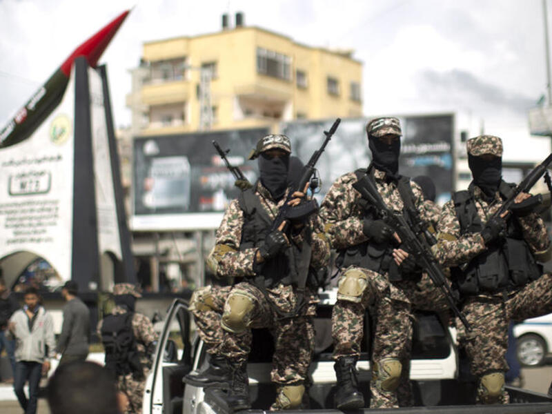 Members of Hamas's military wing pose in front of a M-75 rocket in Gaza. (AFP/ File Photo)