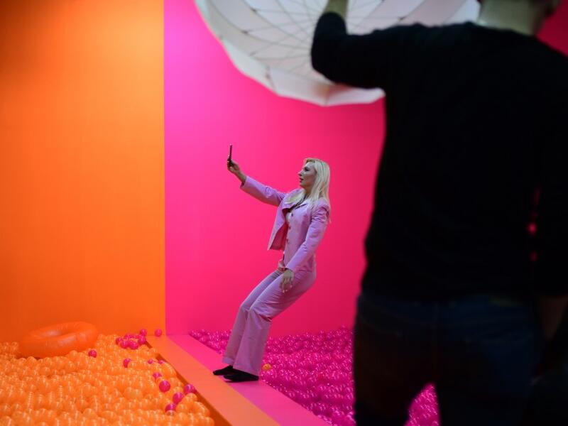 A woman photographs herself as she falls into a ball bath at the "Supercandy Pop-Up Museum Vol. 2" in Cologne, western Germany on November 1, 2019. It is an interactive museum and offers a photo backdrop for social media at 25 stations. INA FASSBENDER / AFP