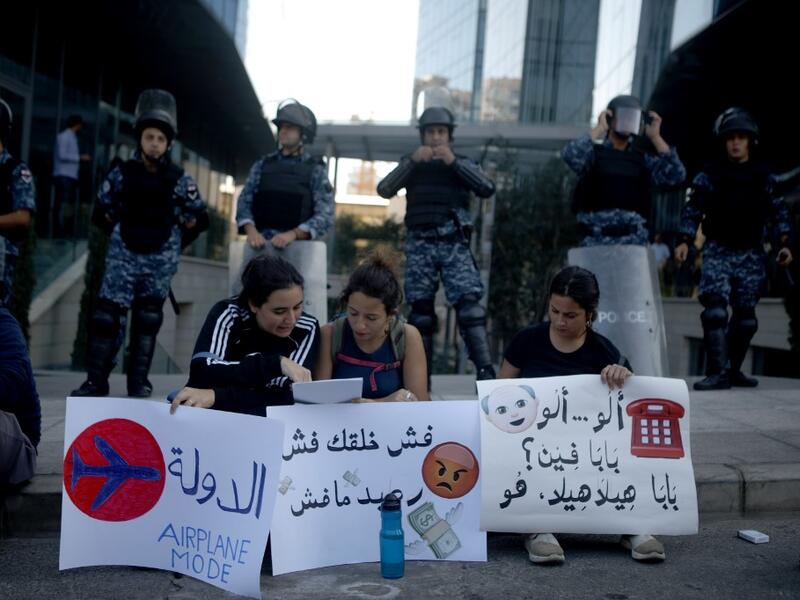 Lebanese anti-government protesters sit in front of riot police at the headquarters of MTC-Touch, a telecom company, in Beirut on November 5, 2019.  (AFP/ File Photo)
