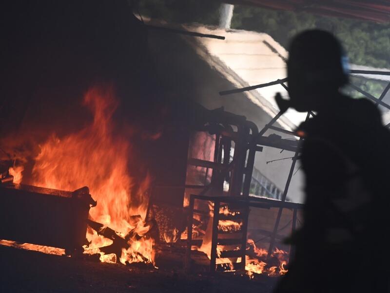 A man walks past burning barricades at the entrance the Hong Kong Polytechnic University during a protest on November 11, 2019. A Hong Kong police officer shot at masked protesters -- hitting at least one in the torso -- during clashes broadcast live on Facebook, as the city's rush hour was interrupted by protests. (Philip FONG / AFP)