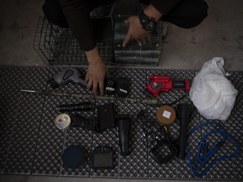 This photo taken on October 23, 2019 shows pet detective Sun Jinrong sitting next to his equipment as he prepares to search for a missing cat in a residential compound in Beijing. Private sleuth Sun Jinrong brings heat detectors, tiny surveillance cameras, and a blowdart loaded with a tranquiliser to his search for one desperate client's missing loved one: A cat named Duoduo.  NOEL CELIS / AFP
