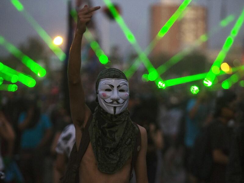 A demonstrator wearing Guy Fawkes mask gestures during a protest against the government, in Santiago on November 18, 2019. (AFP/ File Photo)