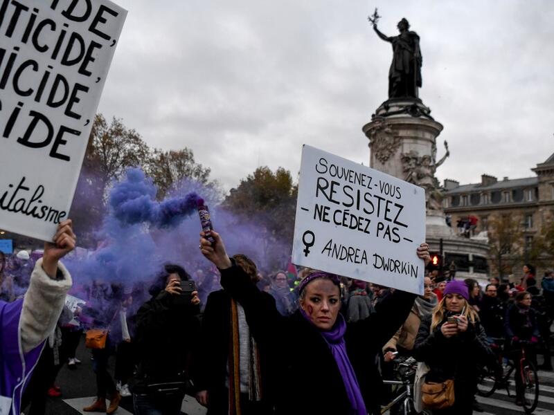 A woman holds a flare and a placard reading "Remember, resist, do not give in" during a protest to condemn violence against women, on November 23, 2019, in Paris. (Alain JOCARD / AFP)
