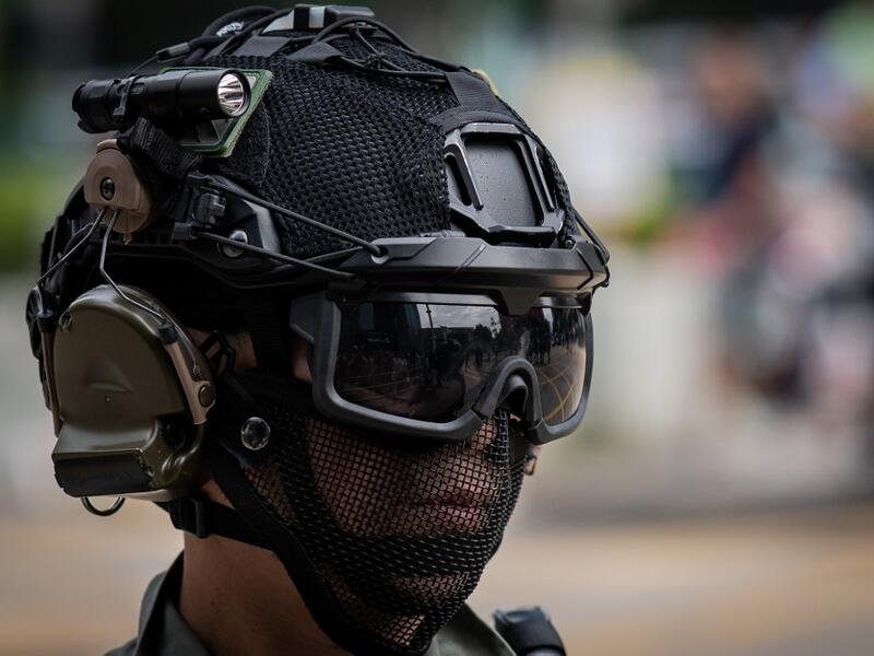 A riot police officer monitors people (not pictured) gathered in the street in support of pro-democracy protesters during a lunch break rally in the Kowloon Bay area in Hong Kong (AFP)