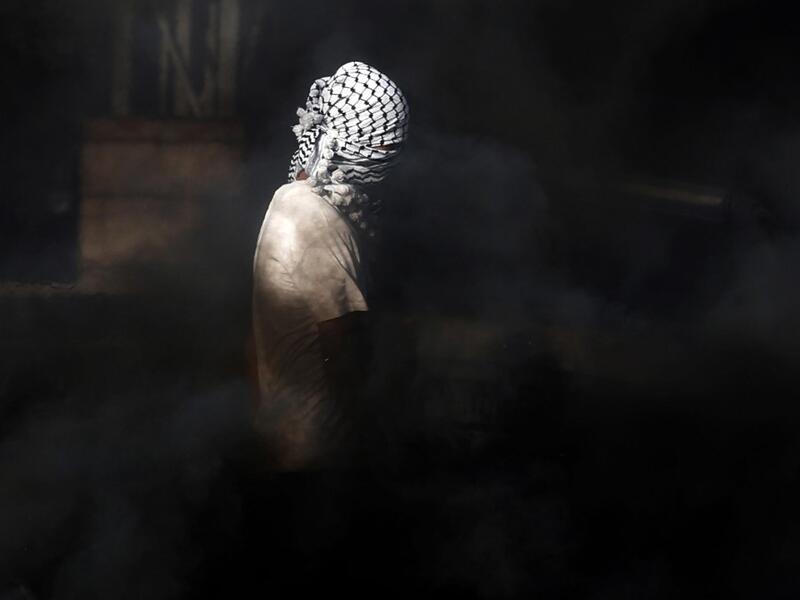 A masked Palestinian youth stands amidst smoke during clashes with Israeli security forces on November 26, 2019 near the West Bank city of Nablus as Palestinians stage a "day of rage" against a recent US decision to no longer consider settlements in the West Bank illegal. The US broke with decades of international consensus on November 18 as its secretary of state announced the country would no longer consider Israeli settlements in the occupied Palestinian territories illegal. Israel, led by its prime mini