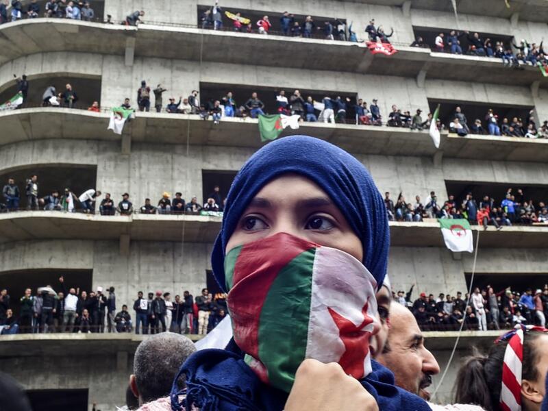A woman covers her face with the national flag, as Algerian protesters demonstrate in the capital Algiers against ailing president's bid for a fifth term on March 8, 2019. Tens of thousands protested across Algeria today in the biggest rallies yet against ailing President Abdelaziz Bouteflika's bid for a fifth term, despite the defiant leader's warning of the risk of "chaos". RYAD KRAMDI / AFP