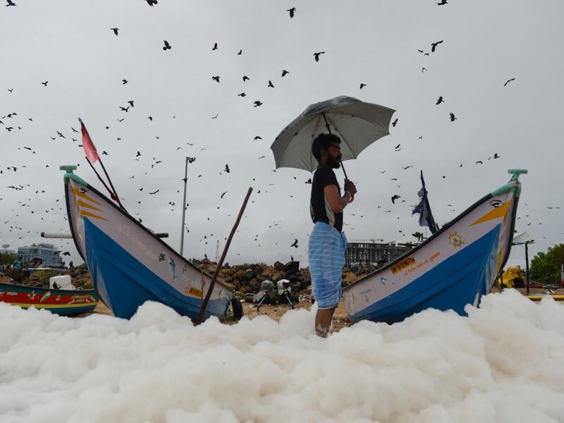 A man looks on as foamy discharge, caused by pollutants, mix with surf at Marina beach in Chennai on December 1, 2019. Arun SANKAR / AFP