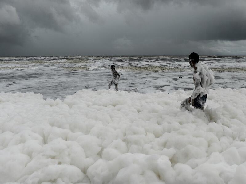 Residents play over foamy discharge, caused by pollutants, as it mixes with the surf at Marina beach in Chennai on December 1, 2019. Arun SANKAR / AFP