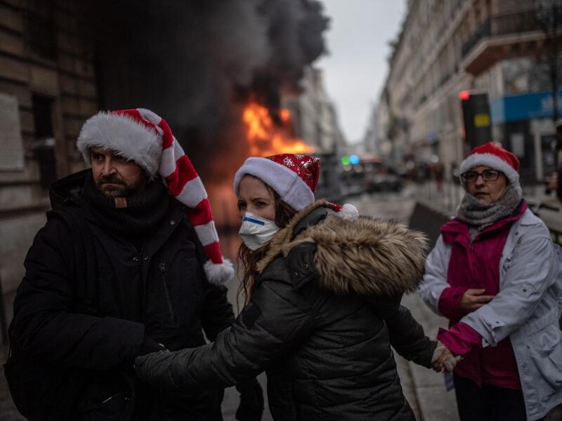 People wearing Christmas hats try to make their way in the streets of Paris during a demonstration over the pension overhauls, on December 5, 2019 as part of a national general strike. BULENT KILIC / AFP