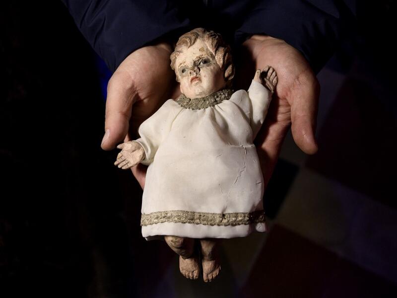 Volunteer Matteo Seia holds a nativity figure of Jesus, one of the most ancient figures of the 43rd edition of the "Presepio of Cavallermaggiore", a 300sqm Christmas Nativity crib in the Oratorio San Michele on December 20, 2019 in Cavallermaggiore, near Cuneo, Northwestern Italy. The "Presepio" is made by ten volunteers who every year spend 3 months to build a new edition with hundred of figures. MARCO BERTORELLO / AFP