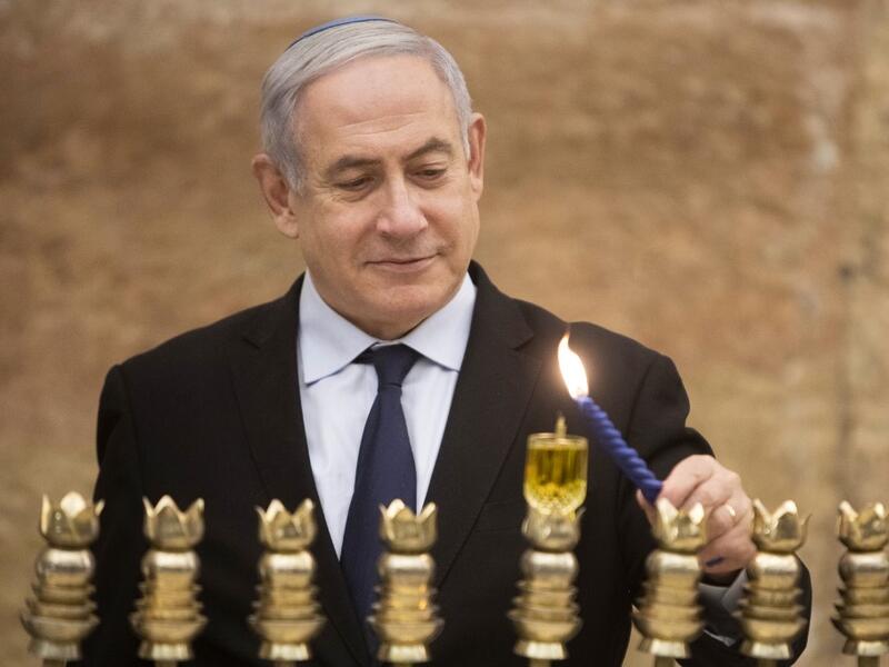 Israeli Prime Minister Benjamin Netanyahu lights a Hanukkah candle at the Western Wall, Judaism's holiest prayer site, in the Old City of Jerusalem on December 22, 2019. Sebastian Scheiner / POOL / AFP