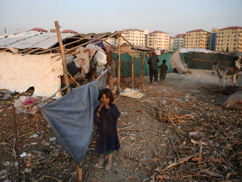 An internally displaced Afghan girl stands outside a temporary home at a refugee camp in Kabul on December 24, 2019. FARSHAD USYAN / AFP