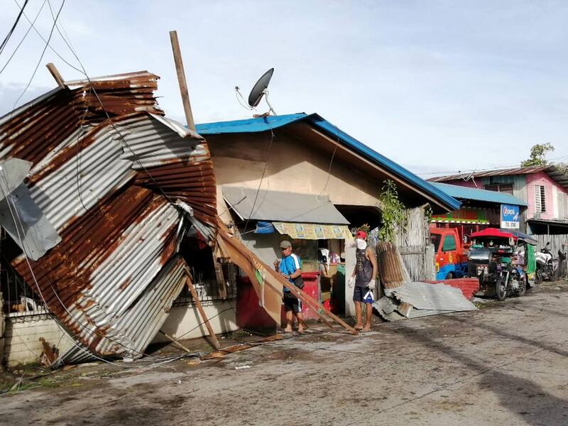Residents stand next to a house damaged by typhoon Phanfone in Ormoc City, Leyte province in central Philippines on December 25, 2019. Typhoon Phanfone pummelled the central Philippines on December 25, bringing a wet, miserable and terrifying holiday season to millions in the mainly Catholic nation. RONALD FRANK DEJON / AFP