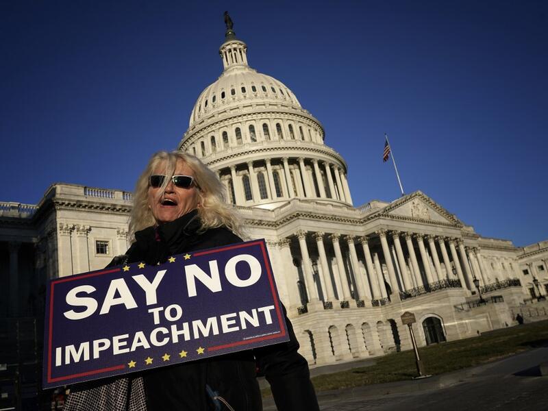 A woman supporting U.S. President Donald Trump walks outside the U.S. Capitol December 18, 2019 in Washington, DC. Later today the U.S. House of Representatives is expected to vote on two articles of impeachment against Trump charging him with abuse of power and obstruction of Congress. Win McNamee/Getty Images/AFP