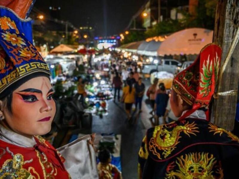 This photograph taken on December 28, 2019 shows actors looking behind the curtains before a Chinese opera performance by Thailand's Sai Bo Hong troupe on a makeshift stage at a street festival in Bangkok. An ancient world of swords, warriors and folklore roars to life on the darkened street, offering a momentary escape from the modern-day bustle of Bangkok's unstoppable development. For centuries, troupes like the Sai Bo Hong Chinese opera have performed throughout Thailand, where 14 percent of the populat
