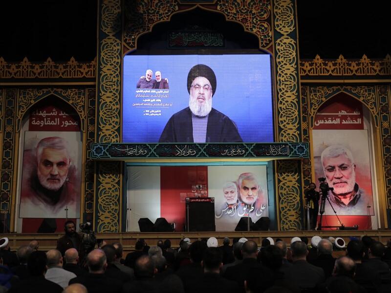 Supporters of the the Shiite Hezbollah movement watch as the movement's leader Hasan Nasrallah delivers a speech on a screen, in the Lebanese capital Beirut's southern suburbs on January 5, 2020. Nasrallah called on Iraq to free itself of the American "occupation" after top Iranian general Qasem Soleimani was killed in a US strike in Baghdad. ANWAR AMRO / AFP