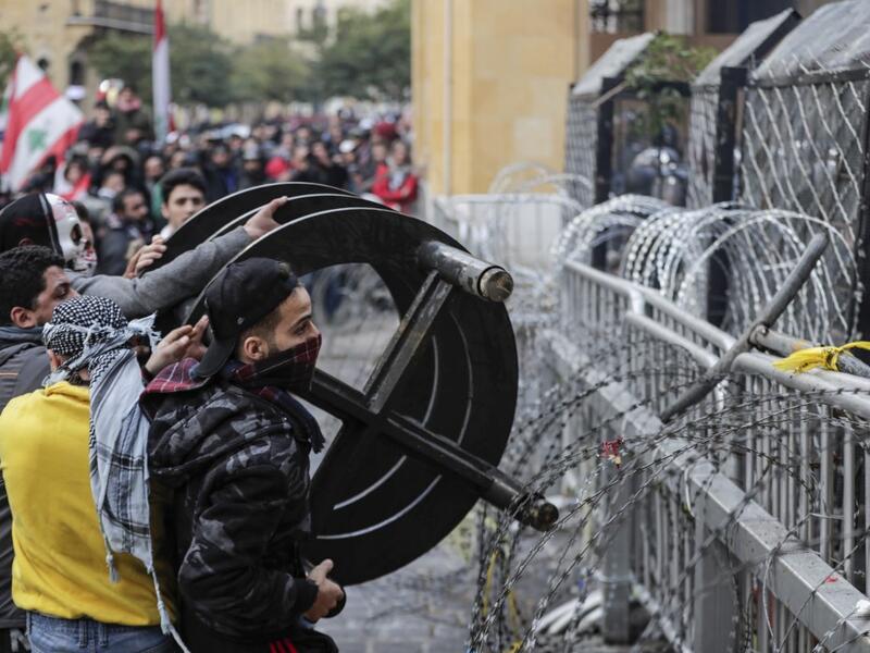 Anti-government protesters attempt to break through the security barrier in the central downtown district of the Lebanese capital Beirut near the parliament headquarters during clashes with security forces on January 18, 2020. ANWAR AMRO / AFP