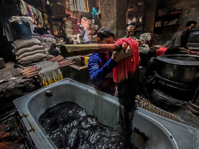 Workers dye yarns at a traditional hand-dying workshop in the Egyptian capital Cairo's centuries old district of Darb al-Ahmar on January 21, 2020. In Cairo's centuries-old Darb al-Ahmar district, Salama Mahmoud Salama's dye workshop is a multi-coloured den of textiles and busy workers colouring all kinds of fabrics. Khaled DESOUKI / AFP