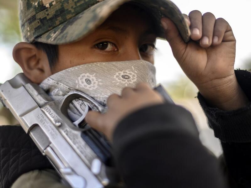 A boy looks on as he holds a gun as the Regional Coordinator of Community Authorities (CRAC-PF) community police force teaches a group of children how to use weapons, at a basketball court in the village of Ayahualtempan, Guerrero State, Mexico, on January 24, 2020. The CRAC-PF vigilante group trains children as young as five so they can protect themselves from drug-related criminal groups operating in the area. AFP