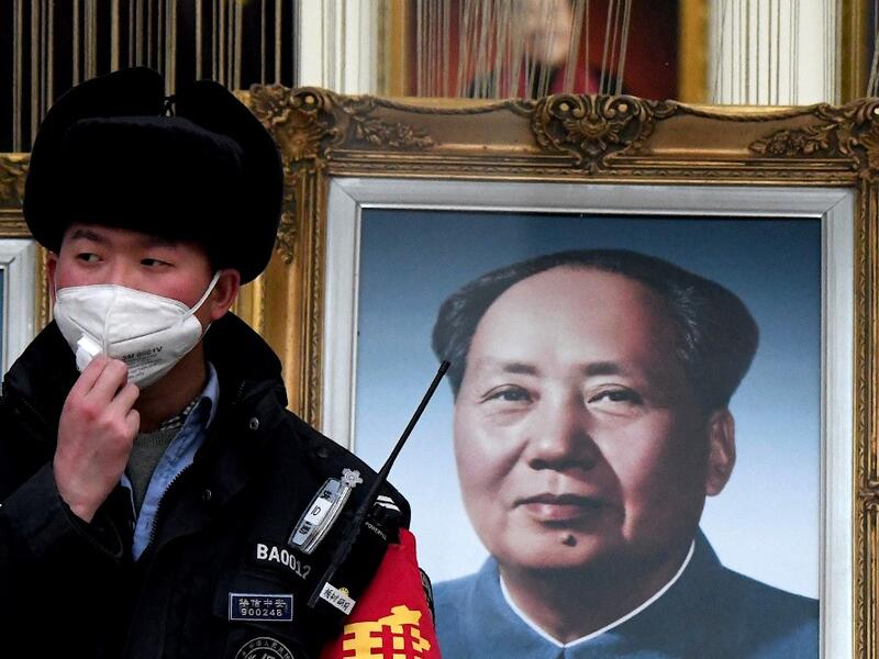 A security guard wearing a facemask to help stop the spread of a deadly virus which began in Wuhan, stands beside a portrait of the late Chinese communist leader Mao Zedong at a shopping centre in Beijing on January 27, 2020. (AFP/ File Photo)