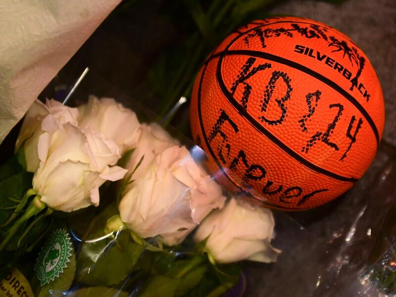 A basketball with the words "KB & 24 Forever" written on it and white roses are placed at a makeshift memorial as fans gather to the mourn the death of NBA legend Kobe Bryant, who was killed along with his daughter and seven others in a helicopter crash on January 26, at LA Live plaza in front of Staples Center in Los Angeles on January 27, 2020. Federal investigators sifted through the wreckage of the helicopter crash that killed basketball legend Kobe Bryant and eight other people, hoping to find clues to