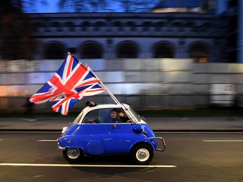 A man waves Union flags from a BMW Isetta as he drives past Brexit supporters gathering in Parliament Square, in central London on January 31, 2020, the day that the UK formally leaves the European Union. Britain on January 31 ends almost half a century of integration with its closest neighbours and leaves the European Union, starting a new -- but still uncertain -- chapter in its long history. DANIEL LEAL-OLIVAS / AFP