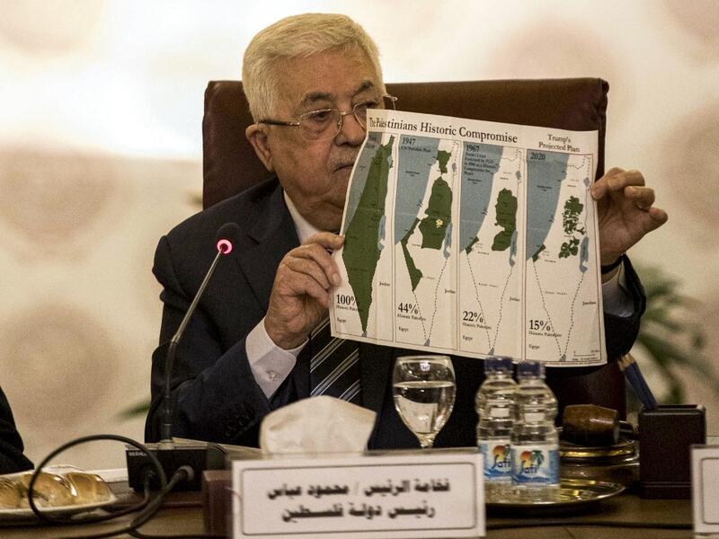 Palestinian president Mahmud Abbas holds a placard showing maps of (L to R) historical Palestine, the 1947 United Nations partition plan on Palestine, the 1948-1967 borders between the Palestinian territories and Israel, and a current map of the Palestinian territories without Israeli-annexed areas and settlements, as he attends an Arab League emergency meeting discussing the US-brokered proposal for a settlement of the Middle East conflict at the league headquarters in the Egyptian capital Cairo on Februar