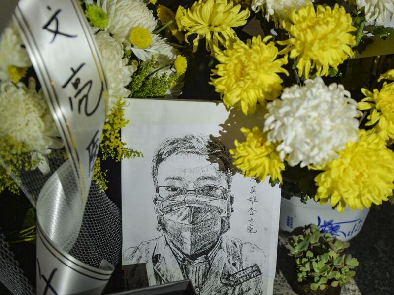 This photo taken on February 7, 2020 shows a photo of the late ophthalmologist Li Wenliang with flower bouquets at the Houhu Branch of Wuhan Central Hospital in Wuhan in China's central Hubei province. AFP
