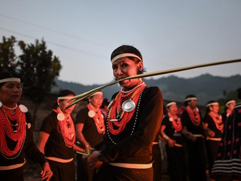 This photo taken on February 7, 2020 shows a Naga tribeswoman biting a coconut leaf at the end of an overnight ceremony to bless the harvest in Satpalaw Shaung village, Lahe township in Myanmar's Sagaing region. A haunting refrain pierces the night as the tribeswomen of the Gongwang Bonyo, among the most isolated people in Myanmar, dance around a campfire to bless the harvest ahead. Ye Aung THU / AFP