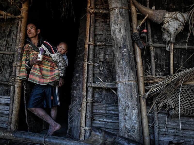 This photo taken on February 5, 2020 shows a man babysitting as his wife carries wood for the upcoming overnight ceremony by Naga tribeswomen to bless the harvest in Satpalaw Shaung village, Lahe township in Myanmar's Sagaing region. A haunting refrain pierces the night as the tribeswomen of the Gongwang Bonyo, among the most isolated people in Myanmar, dance around a campfire to bless the harvest ahead. Ye Aung THU / AFP