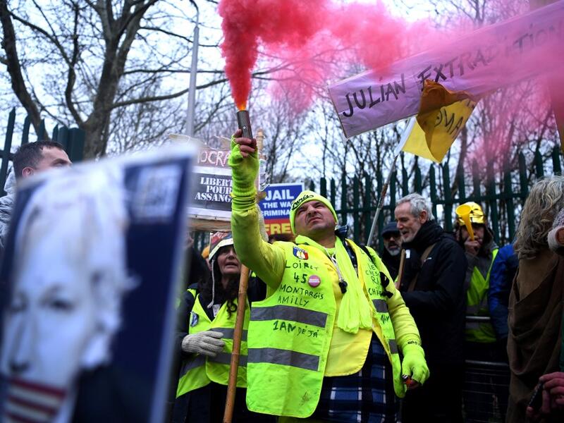 A supporter of WikiLeaks founder Julian Assange, wearing a French themed "yellow vest" or gilets jaunes, holds a flare as he calls for Assange's freedom outside Woolwich Crown Court and HMP Belmarsh prison in southeast London on February 24, 2020, on the opening day of the trial to hear a US request for Assange's extradition. AFP