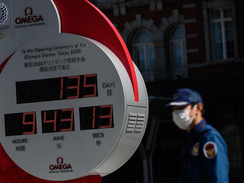 A security guard wearing a face mask walks in front of the Olympic countdown clock outside Tokyo station on March 11, 2020. Japan and Olympic organisers are at pains to insist this summer's Games in Tokyo are on, despite the new coronavirus outbreak. Philip FONG / AFP