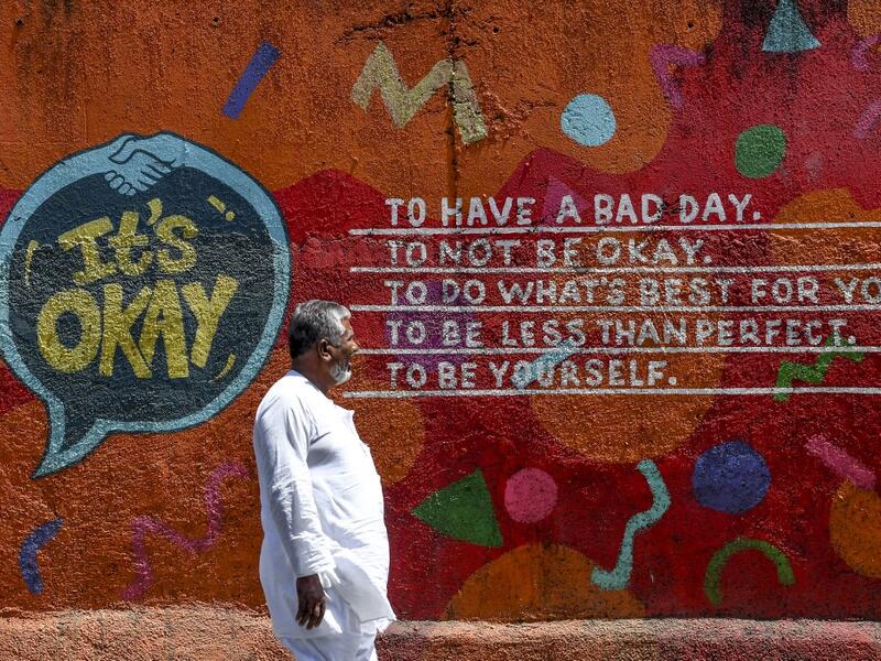 A man walks past a graffiti with a positive message painted on a wall in a street in Mumbai on March 14, 2020. INDRANIL MUKHERJEE / AFP