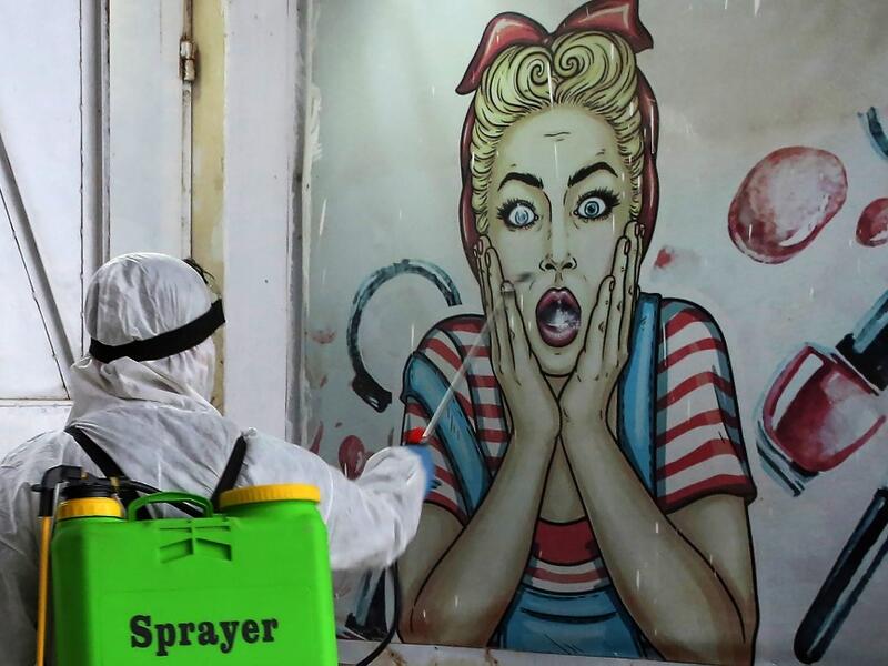 A volunteer disinfects a shop in Baghdad's Bayaa neighbourhood on March 21, 2020 as a preventive measure against the spread of the coronavirus COVID-19. AHMAD AL-RUBAYE / AFP