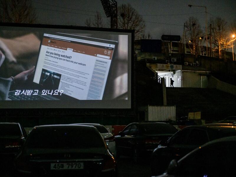 In a photo taken on March 21, 2020 a screen shows a movie at a drive-through cinema in Seoul. Box office numbers in South Korea -- which has 8,897 confirmed virus cases -- have plummeted in recent weeks due to the epidemic, with authorities urging the public to avoid large crowds. But at drive-in cinemas, moviegoers can enjoy a movie from the comfort of their cars, parked in front of a large outdoor screen.  Ed JONES / AFP