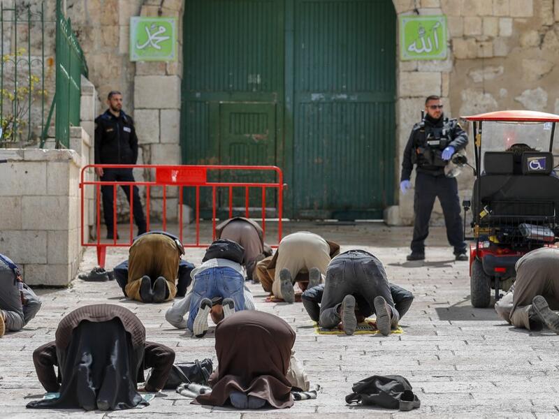 This picture taken on March 23, 2020 shows Palestinian Muslim men prostrate in prayer as Israeli security forces watch near the closed gate of the Aqsa mosque compound, which was closed by the Jordan Waqf religious authority administering the site as part of preventive measures against the spread of the COVID-19 novel coronavirus, in Jerusalem. Over a 24-hour period, in a world where a third of humanity is now under orders to stay home, AFP photographers have captured snapshots of daily life during the coro