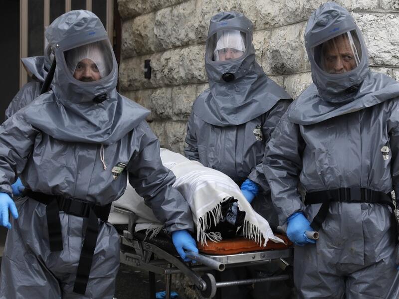 Workers at Israel's religious burial society Chevra Kadisha wearing protective equipment, carry the body of a patient who died from complications of Coronavirus (COVID-19) infection, at the Shamgar Funeral Home in Jerusalem, on April 1, 2020. Ahmad GHARABLI / AFP
