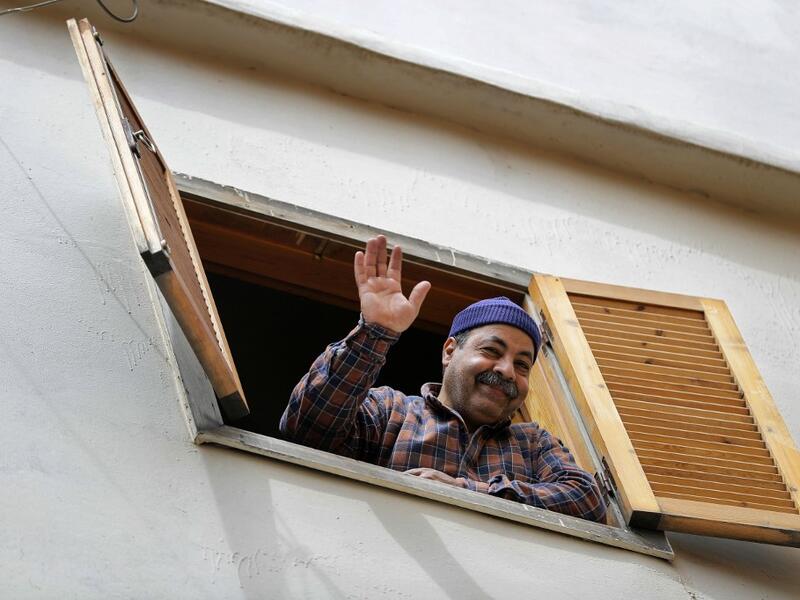 A Lebanese man waves in greeting from his window during confinement at home due to the COVID-19 pandemic, in the historic part of the southern coastal city of Sidon (Saida), on April 6, 2020. Lebanon's President called on international donors to provide financial assistance to the crisis-hit country as it grapples with a severe economic downturn compounded by the novel coronavirus pandemic. JOSEPH EID / AFP