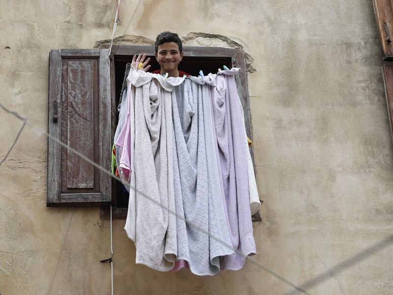 A Lebanese youth waves in greeting as he looks out of a window during confinement at home due to the COVID-19 pandemic, in the historic part of the southern coastal city of Sidon (Saida), on April 6, 2020. Lebanon's President called on international donors to provide financial assistance to the crisis-hit country as it grapples with a severe economic downturn compounded by the novel coronavirus pandemic. JOSEPH EID / AFP