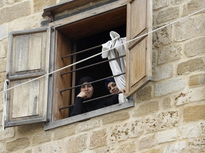 Lebanese women look out of a window during confinement at home due to the COVID-19 pandemic, in the historic part of the southern coastal city of Sidon (Saida), on April 6, 2020. Lebanon's President called on international donors to provide financial assistance to the crisis-hit country as it grapples with a severe economic downturn compounded by the novel coronavirus pandemic. JOSEPH EID / AFP