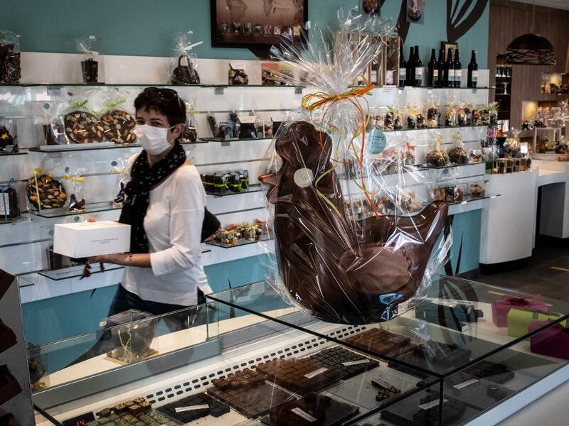 A client with a face mask leaves the shop of pastry and chocolate maker Didier Girard after buying Easter chocolates in Vourles, near Lyon at on April 7, 2020, on the twenty-second day of a strict lockdown in France to stop the spread of COVID-19, caused by the novel coronavirus. JEAN-PHILIPPE KSIAZEK / AFP