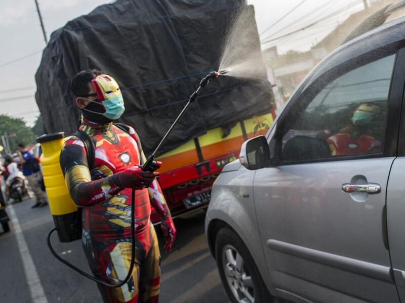 An Indonesian police officer wearing a superhero costume on the street disinfects motorists' vehicles in Pasuruan, East Java on April 9, 2020, amid concert to the COVID-19 coronavirus. JUNI KRISWANTO / AFP