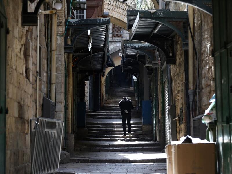 A man wearing disposable gloves amid the COVID-19 pandemic, walks the empty Via Dolorosa, or Way of the Cross, believed to be the route Jesus walked carrying the cross on the way to crucifixion, in Jerusalem's Old City, on April 7, 2020. All cultural sites in the Holy Land are shuttered, regardless of their religious affiliation, as authorities seek to forestall the spread of the deadly respiratory disease, which will prevent Christians from congregating for the Easter service, this coming Sunday for Cathol